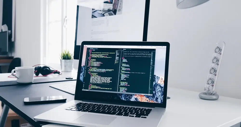 Notebook com código na tela sobre mesa de trabalho, cena de desenvolvimento para geradores de cartão de crédito para teste